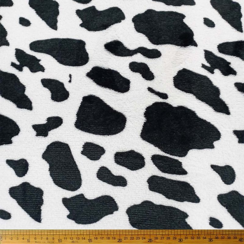 A swatch or roll of Printed Mongolian Fleece with a "Cow" print pattern (e.g., black and white patches), showing its plush texture.